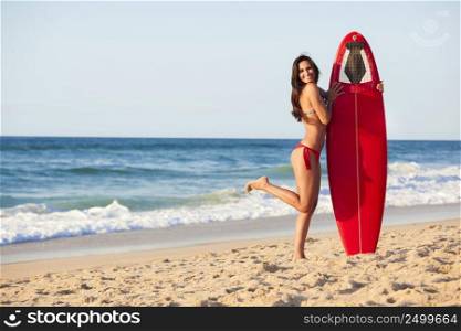 A beautiful surfer girl at the beach holding up her surfboard. Surfer Girl