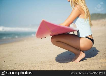 A beautiful surfer girl looking at the beach with her surfboard