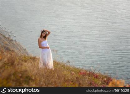 A beautiful tall slender girl stands on a hill by the sea