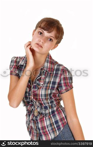 A beautiful teenage girl standing in the studio, holding her head with onehand, in a checkered blouse for white background.