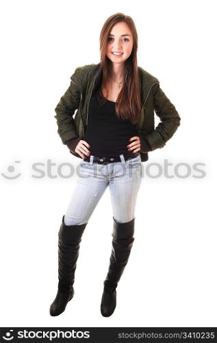 A beautiful teenager girl in a green winter jacket and long black bootsand long brunette hair smiling into the camera.