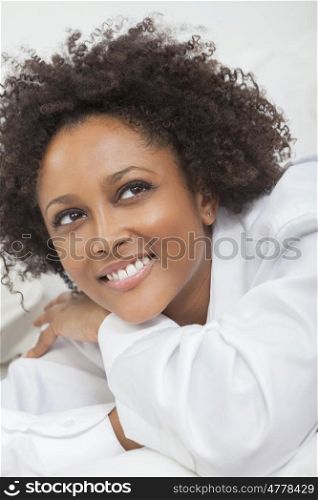 A beautiful thoughtful happy mixed race African American girl or young woman wearing a white shirt looking up smiling with perfect teeth