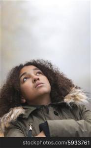 A beautiful thoughtful sad thinking mixed race African American girl or young woman looking up outside on a foggy or misty day