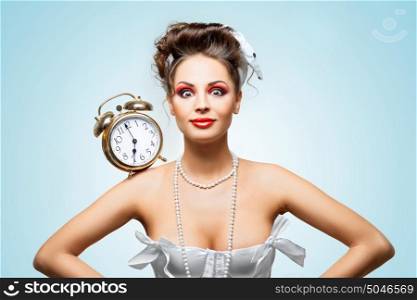 A beautiful vintage girl in a white wedding dress with a retro alarm clock on her shoulder in the morning.