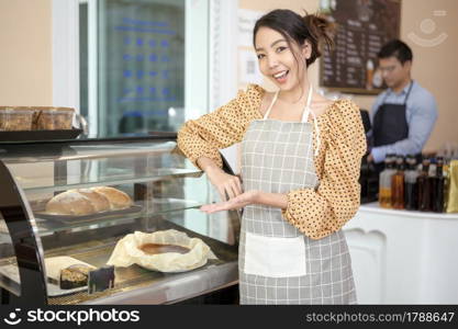 A beautiful woman bakery or coffee shop owner is smiling in her shop