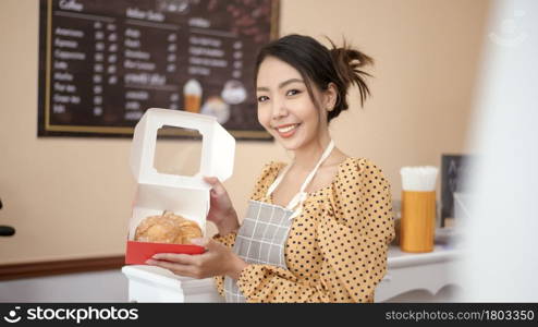 A beautiful woman bakery or coffee shop owner is smiling in her shop