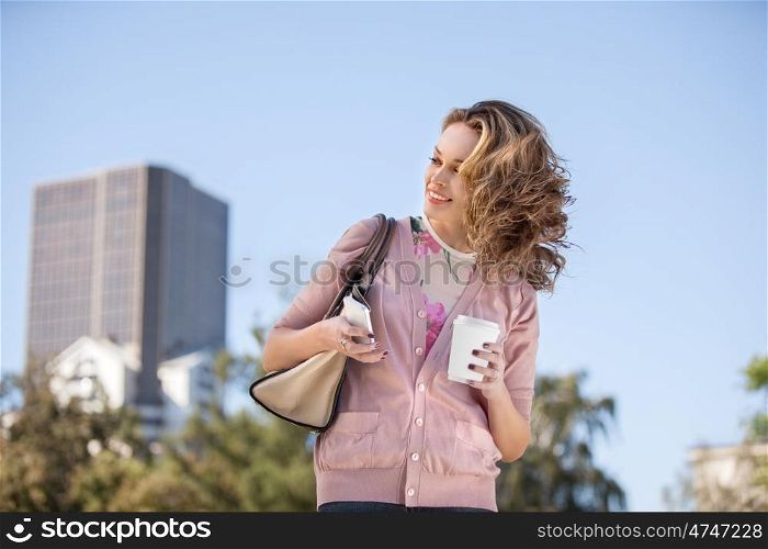 A beautiful woman checking email via mobile phone in a city park.