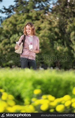A beautiful woman checking email via mobile phone in a city park.