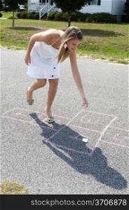 A beautiful woman engaged in the childhood game of hopscotch