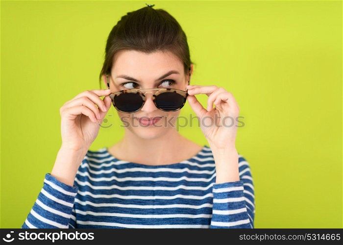a beautiful woman  in sunglasses posing in front of a green background
