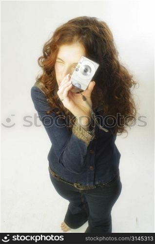 A beautiful woman poses with a digital camera taking a photo.