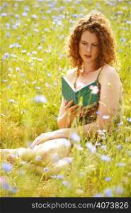 A beautiful woman reading a book in a field of flowers