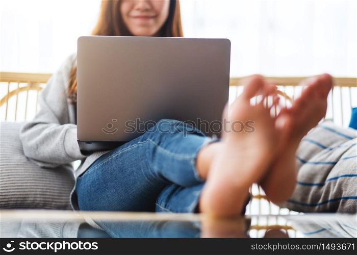 A beautiful woman using and working on laptop computer while sitting on a sofa at home