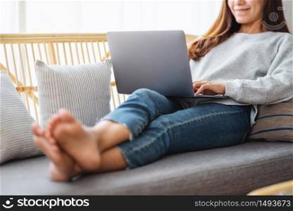 A beautiful woman using and working on laptop computer while sitting on a sofa at home