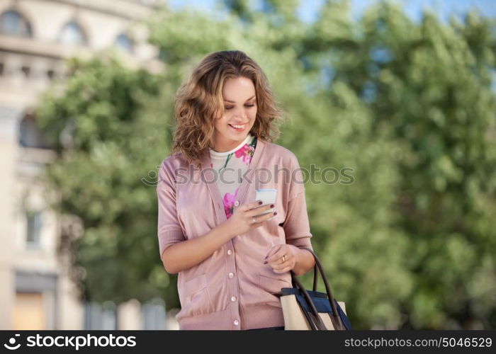 A beautiful woman using wireless internet and checking email via mobile phone in a big city.