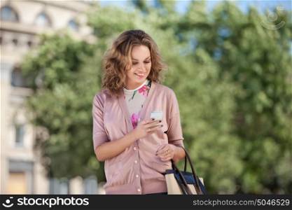 A beautiful woman using wireless internet and checking email via mobile phone in a big city.