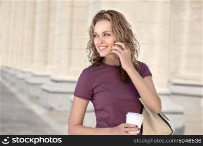 A beautiful woman with the phone holding a cup of take away coffee.