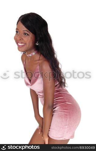 A beautiful young African woman standing in a short pink dress,bending forwards, isolated for white background