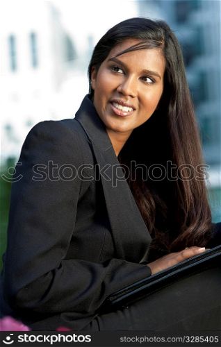 A beautiful young Asian businesswoman with a folder and a wonderful smile shot outside in golden sunshine