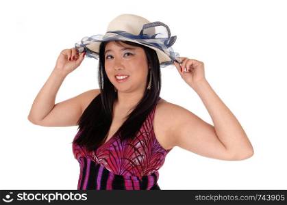 A beautiful young Asian woman standing in a dress and long black hair holding her hands on her hat, isolated for white background
