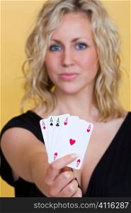 A beautiful young blond woman smiling with a hand of four aces, the focus here is on the cards.