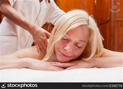A beautiful young blonde woman receiving a shoulder massage