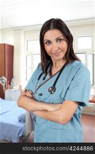 A beautiful young brunette female doctor or nurse standing in a hospital room.