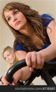 A beautiful young brunette woman on an exercise bike/spinning bike at the gym