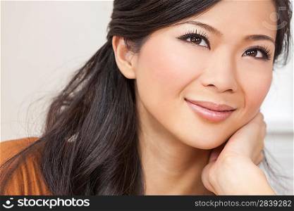 A beautiful young Chinese Asian Oriental woman resting on her hand with a wonderful smile