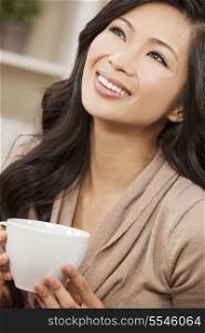 A beautiful young Chinese Asian Oriental woman with a wonderful toothy smile drinking tea or coffee from a white cup