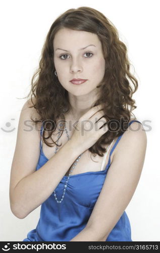 A beautiful young female model in a blue top holds her hand across her chest