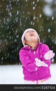 A beautiful young girl having fun playing in the snow