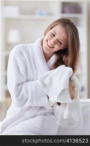 A beautiful young girl in a bathrobe wipes her hair with a towel
