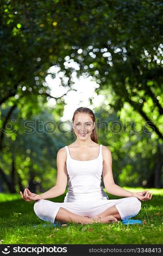 A beautiful young girl in lotus pose in the park
