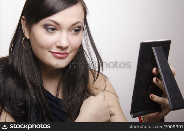 A beautiful young girl looks in the mirror. The girl is very happy with the make-up.