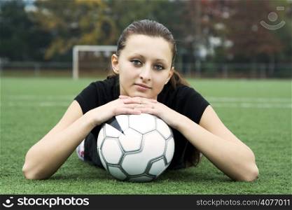 A beautiful young girl resting on a soccer ball