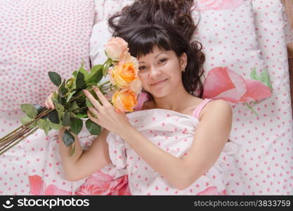 A beautiful young girl who lies in bed, gave flowers