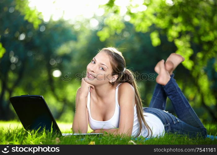 A beautiful young girl with laptop in the park