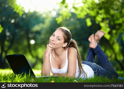 A beautiful young girl with laptop in the park
