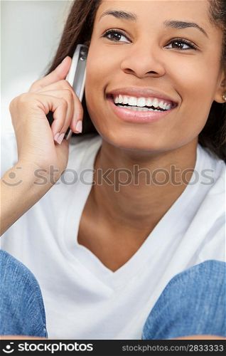 A beautiful young happy African American young woman or girl with a wonderful smile chatting on her cell phone.