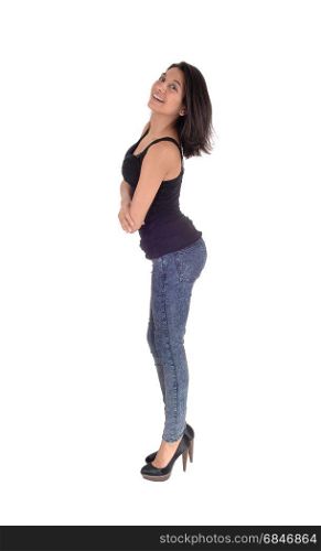 A beautiful young Hispanic woman standing in profile in a black t-shirtand jeans, looking into the camera, isolated for white background.