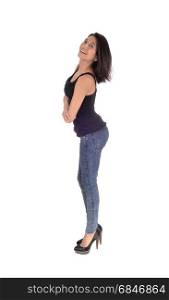 A beautiful young Hispanic woman standing in profile in a black t-shirtand jeans, looking into the camera, isolated for white background.