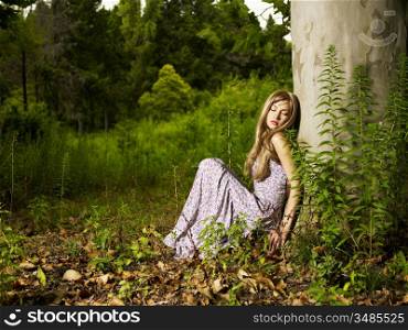 A beautiful young lady sitting in a tree in the forest