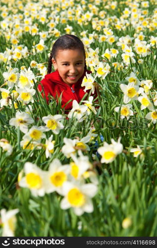 A beautiful young mixed race girl playing in a field of daffodils