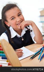 A beautiful young mixed race girl writing in a school classroom surrounded by books and an abacus