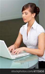 A beautiful young oriental woman using a laptop in a modern office