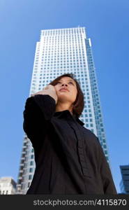 A beautiful young oriental woman with a wonderful on her cell phone in a modern skyscraper filled city.