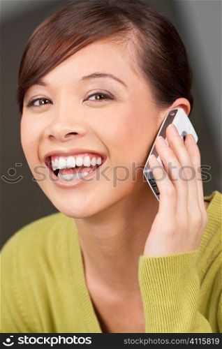 A beautiful young oriental woman with a wonderful smile chatting on her cell phone.