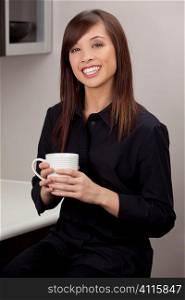 A beautiful young oriental woman with a wonderful toothy smile drinking from a white mug