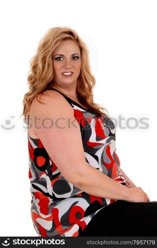 A beautiful young plus size woman in a nice dress and curly blond hairsitting isolated for white background.